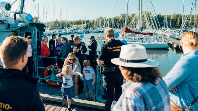 paljon ihmisiä rajavartiolaitoksen laivan kannella venesatamassa