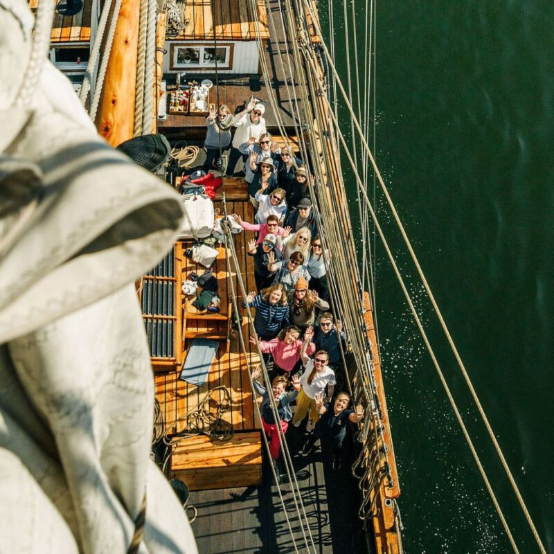 paljon ihmisiä katsomassa ylös ja vilkuttamassa purjelaivan kannella